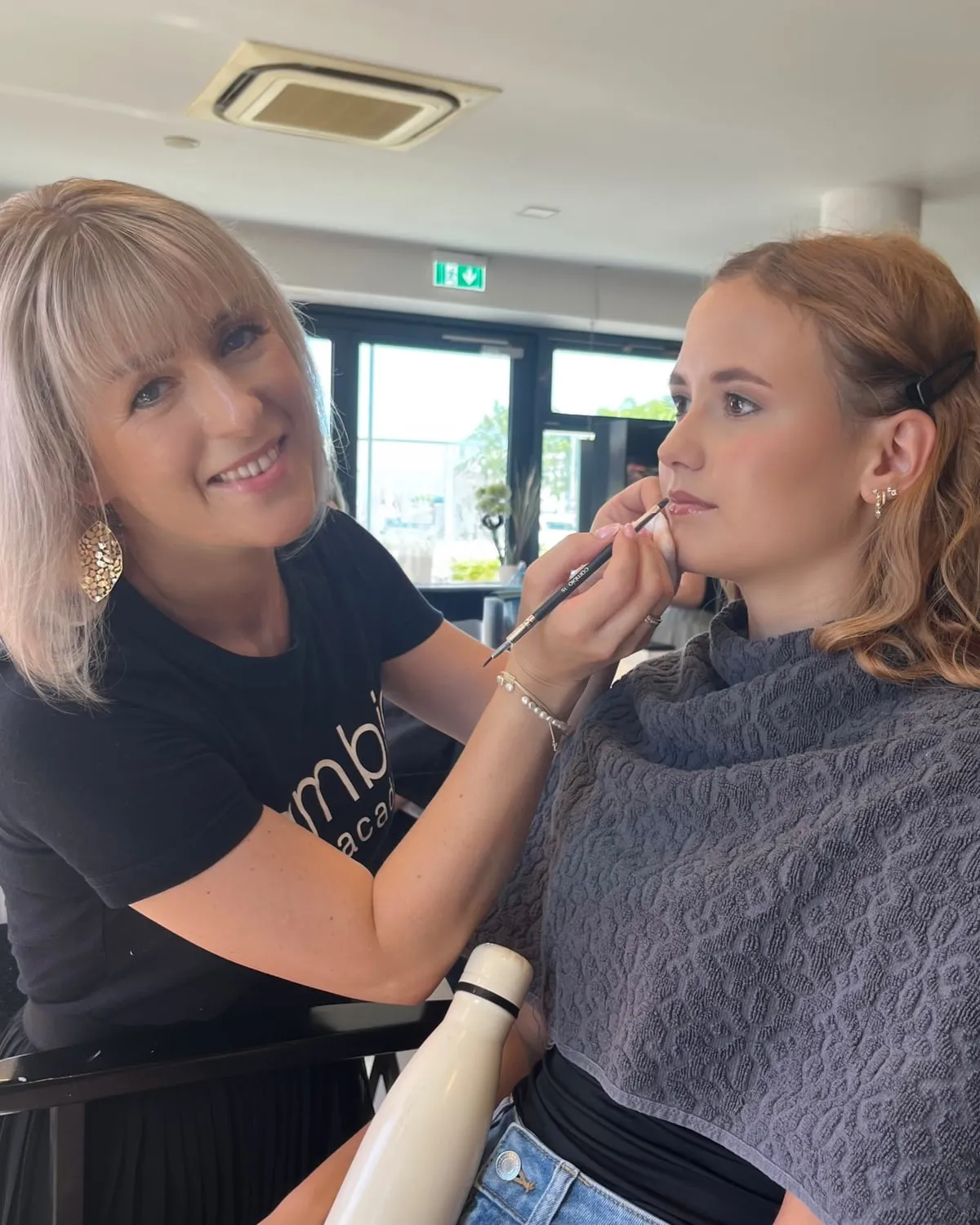 Christina trägt einer Kundin mit einem feinen Pinsel Lippenfarbe auf