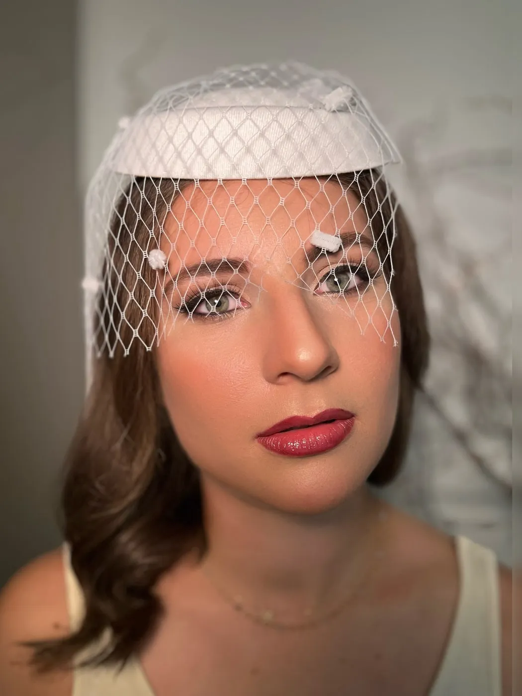 Braut-Make-up mit weißem Birdcage-Schleier und dunklen Locken
