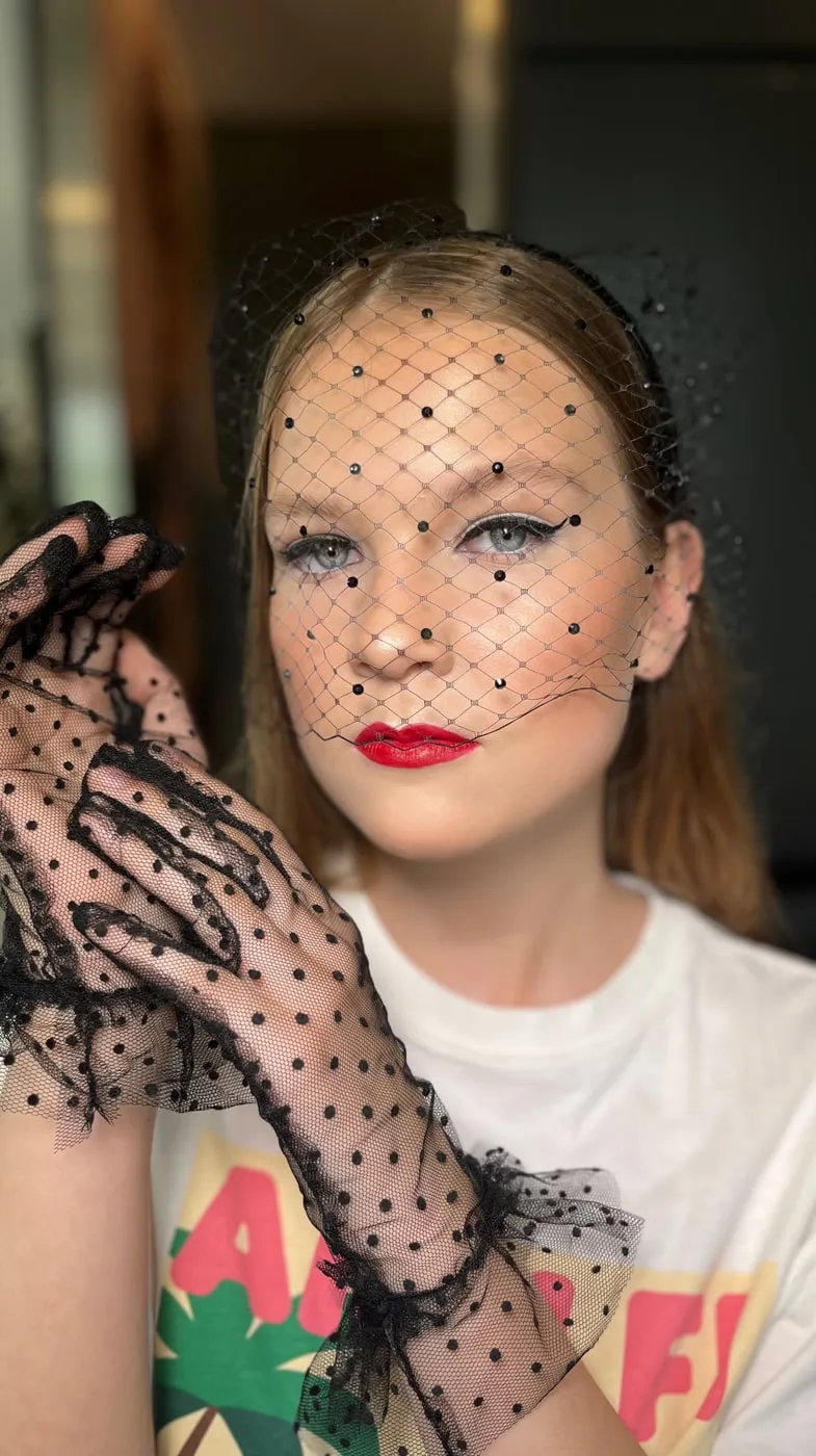 Editorial-Look mit Punkte-Schleier, Spitzenhandschuhen und roten Lippen