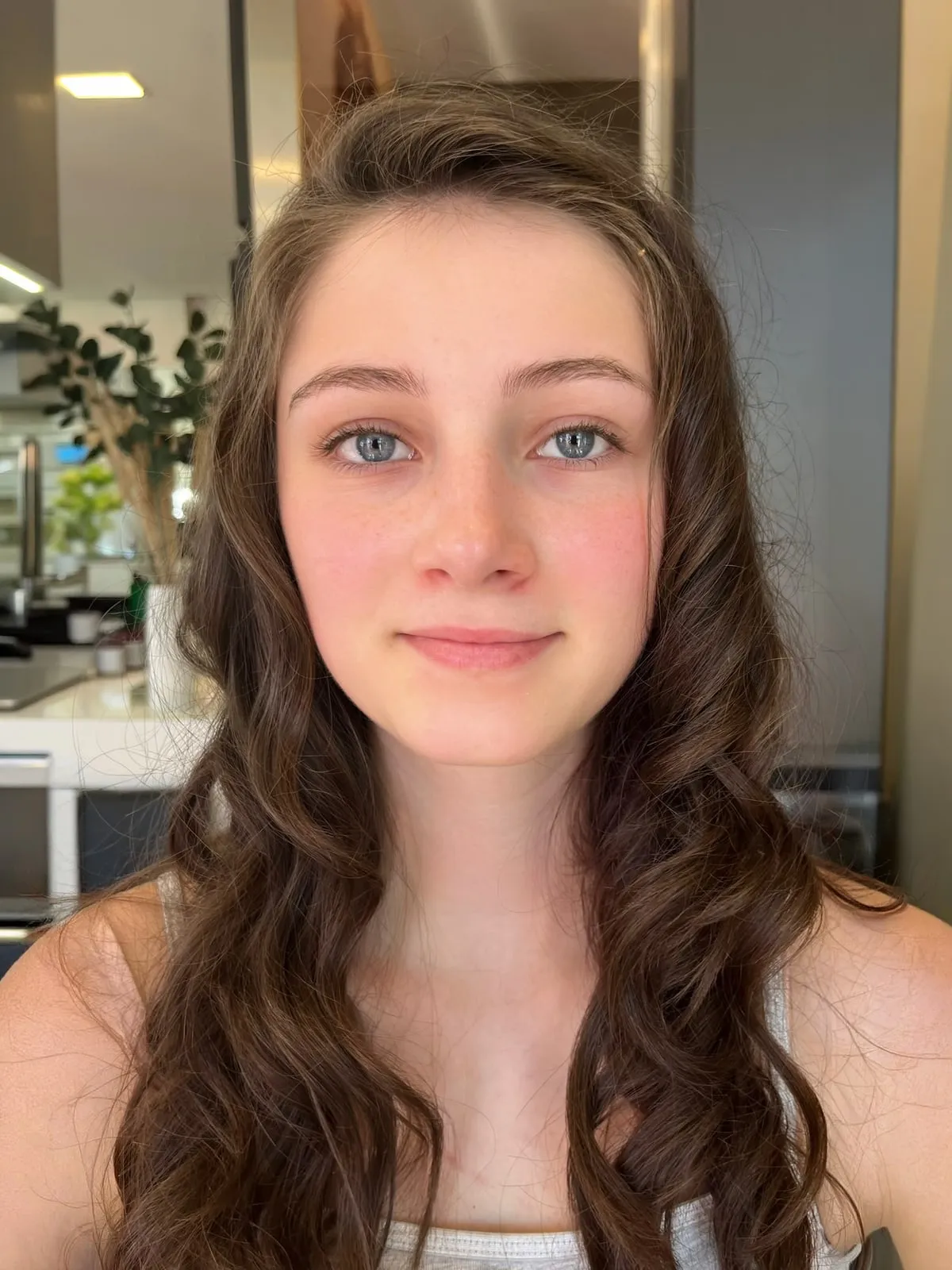 Dieselbe junge Frau ungeschminkt mit offenen dunklen Locken, vor dem Abend-Make-up