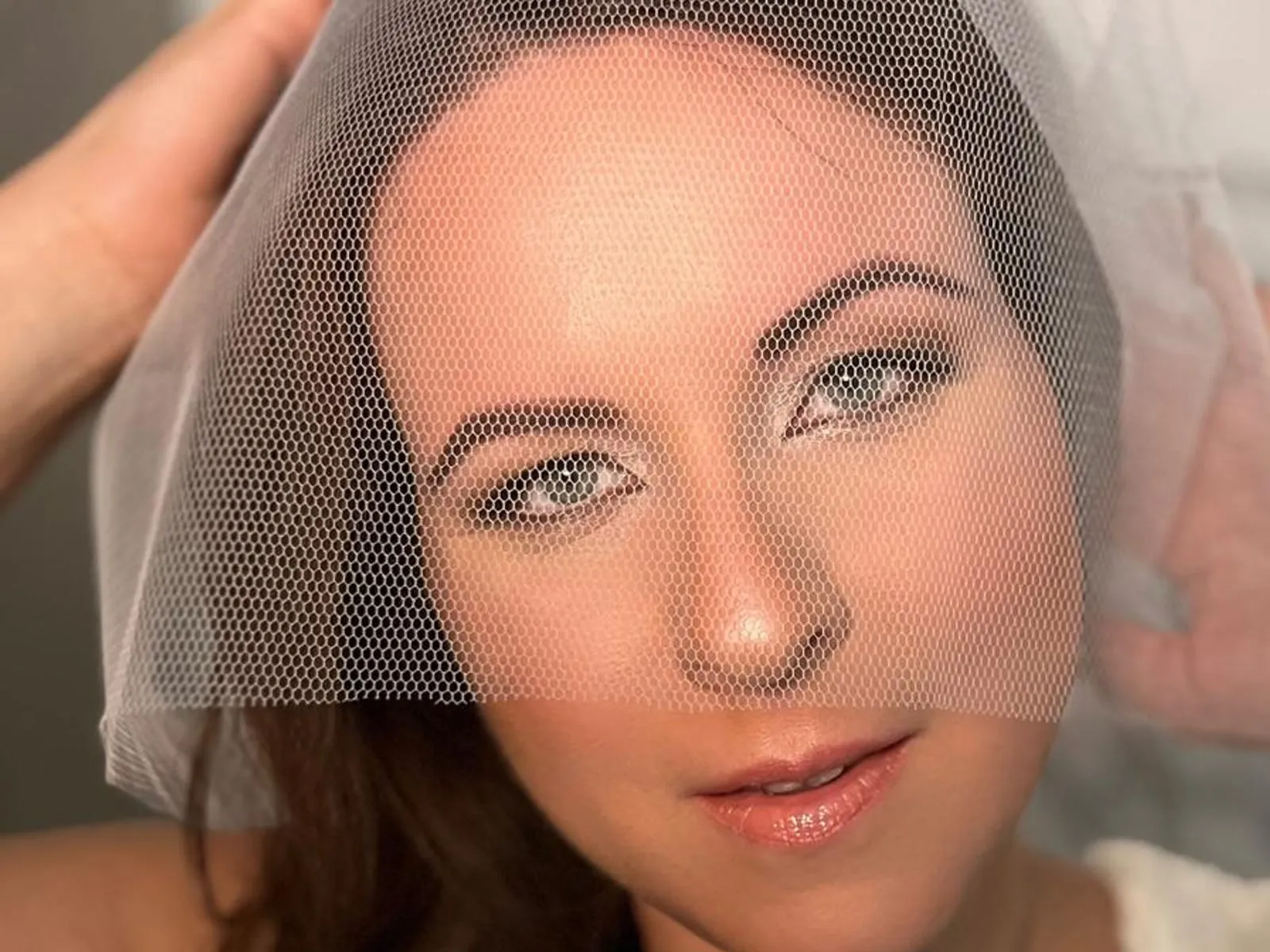 Braut-Make-up von Beauty by Christina: Braut blickt durch einen zarten Tüllschleier in die Kamera, natürliches Glow-Make-up